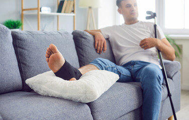 man sitting on couch with ankle injury