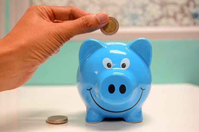 someone placing money in blue piggy bank