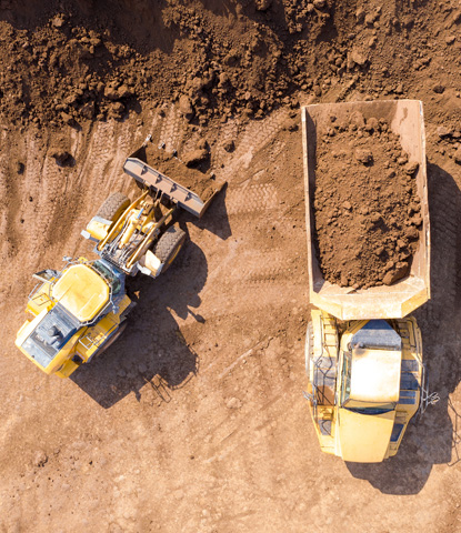 Excavator loading soil onto an Articulated hauler Truck Top down aerial image