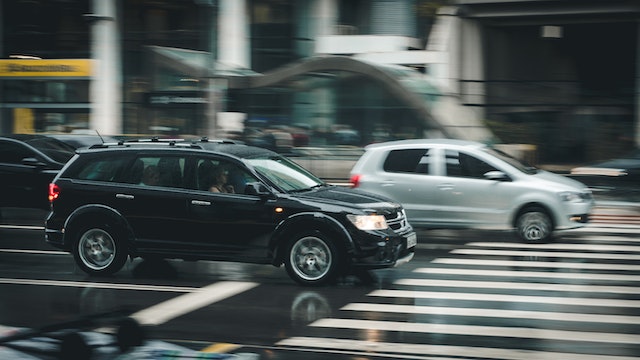 silver car passing black SUV