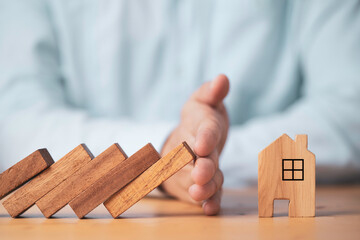 wooden blocks falling towards house but hand protecting the house